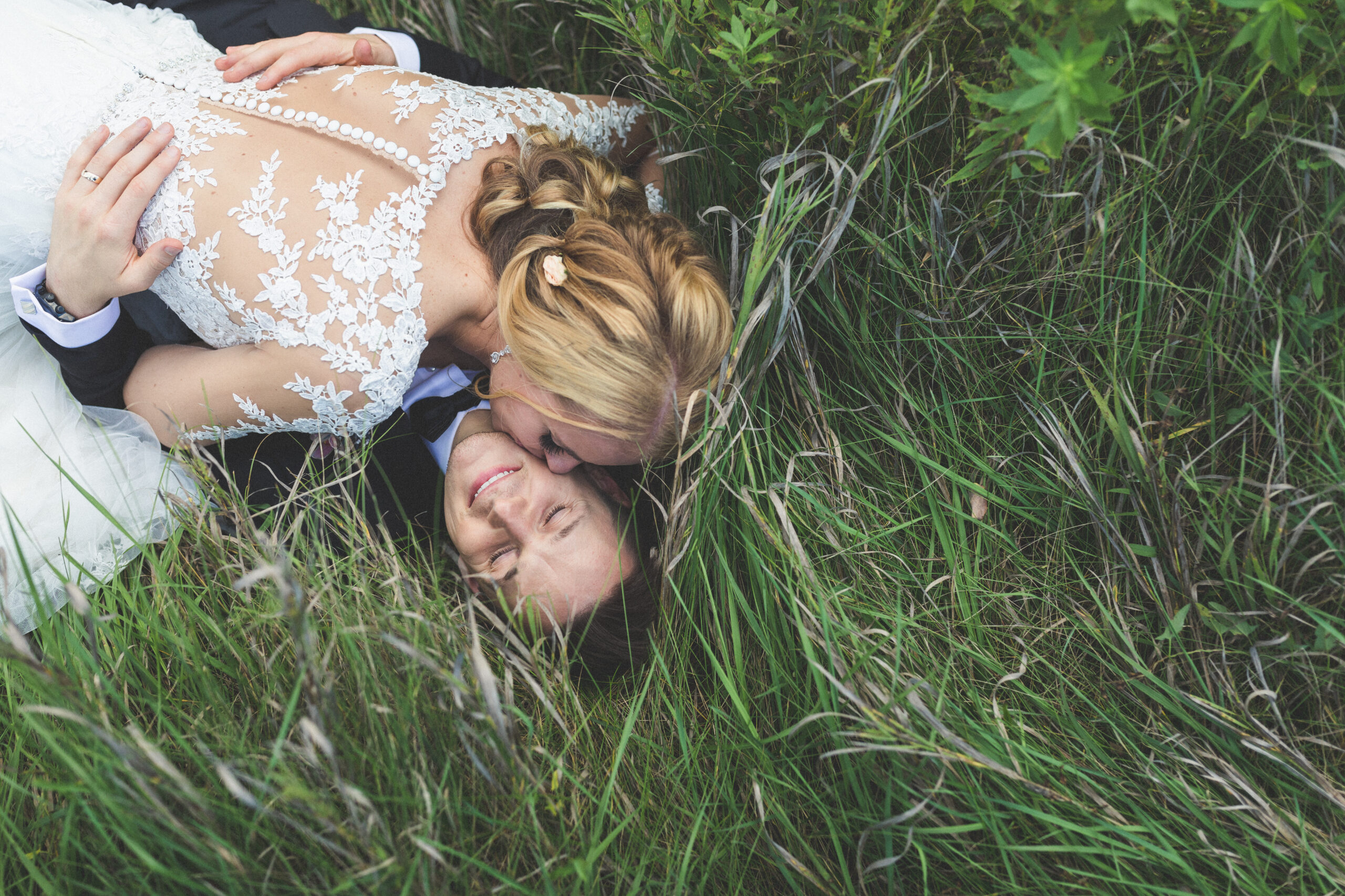 Bride & Groom laying in the grass on wedding day