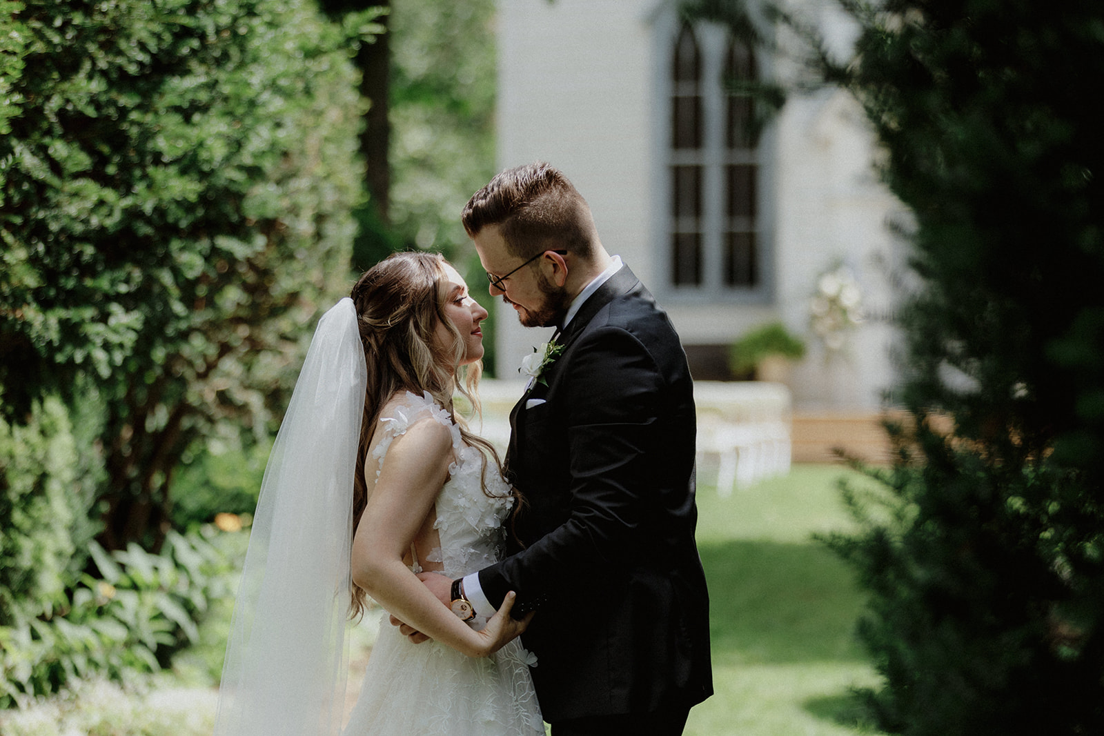 A bride and groom share a tender moment outdoors.